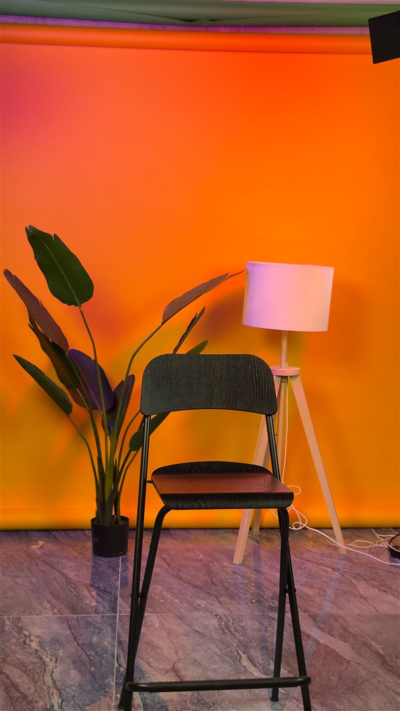 Fondo naranja con taburete y planta